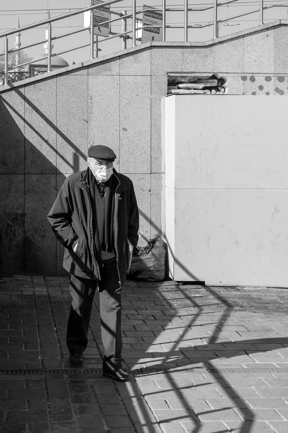 man in black coat standing on sidewalk during daytime