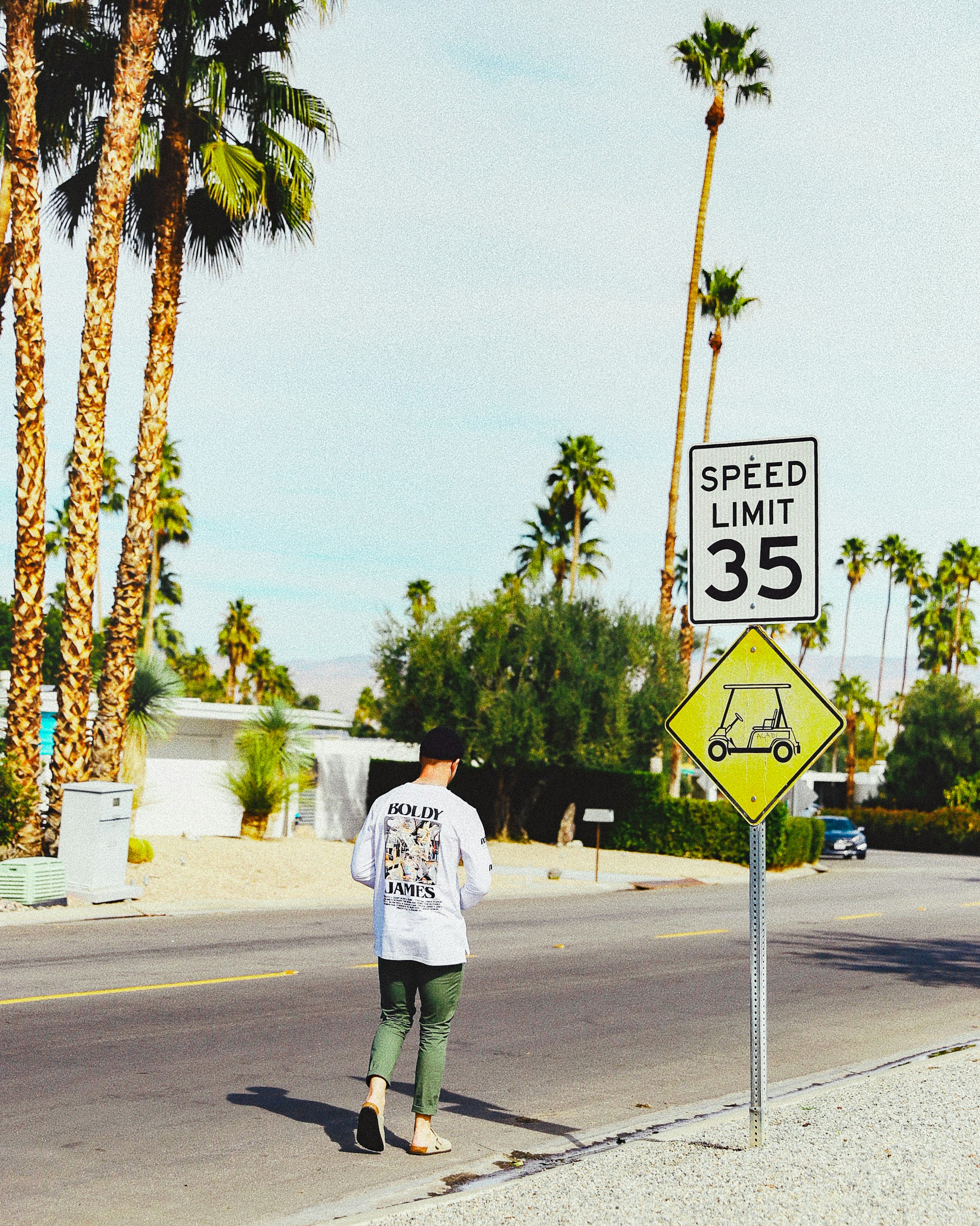 man in white shirt and black pants standing on road during daytime