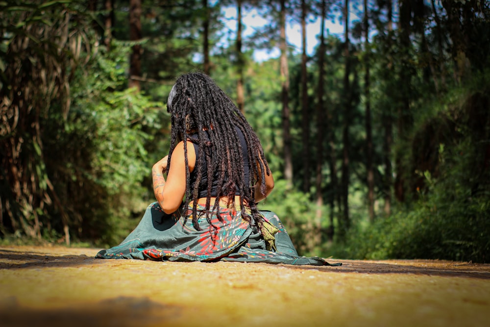 woman in black and orange dress sitting on brown rock