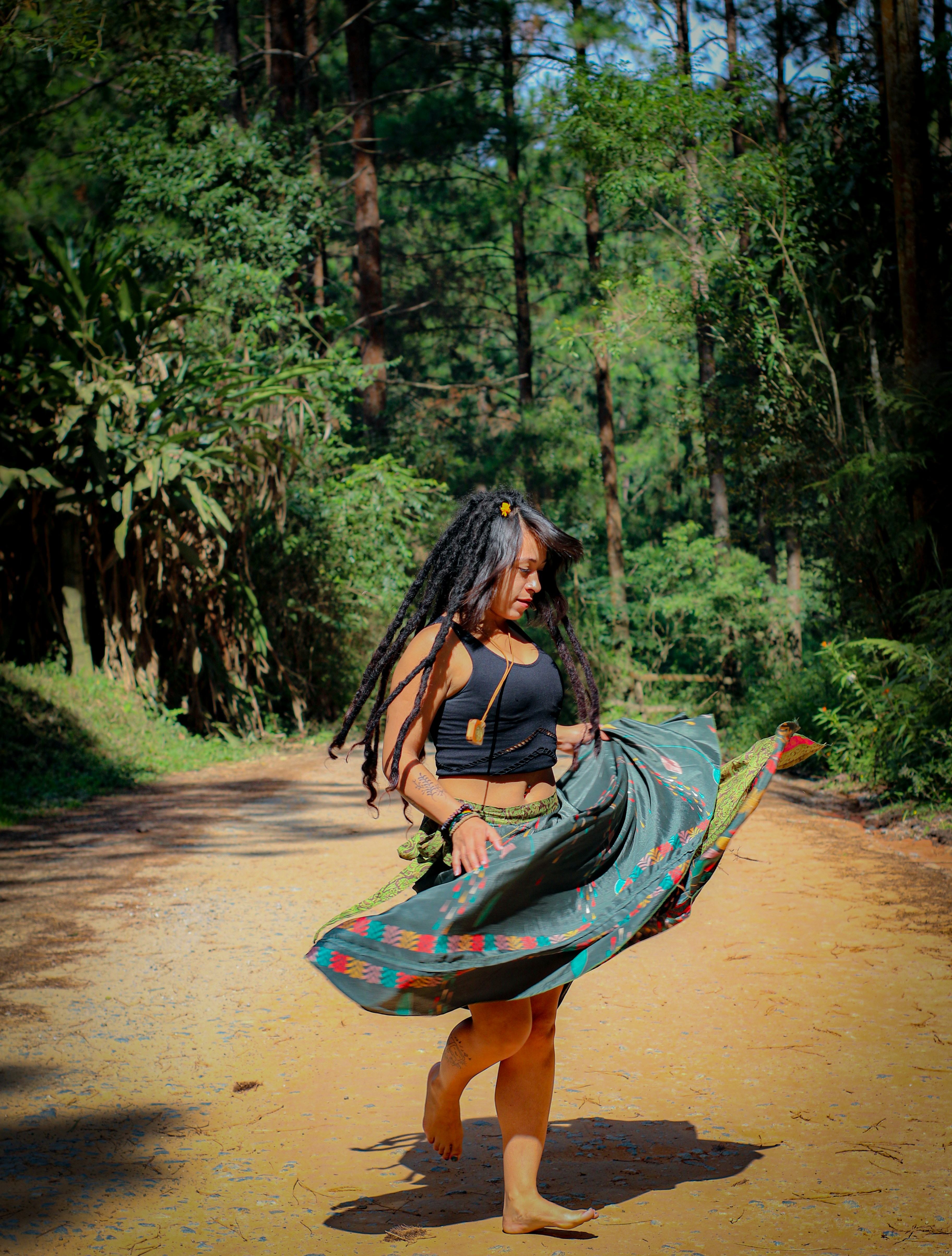woman in blue and white dress walking on dirt road during daytime