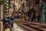man in black jacket sitting on bench beside yellow train during daytime
