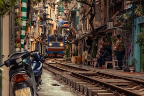 man in black jacket sitting on bench beside yellow train during daytime