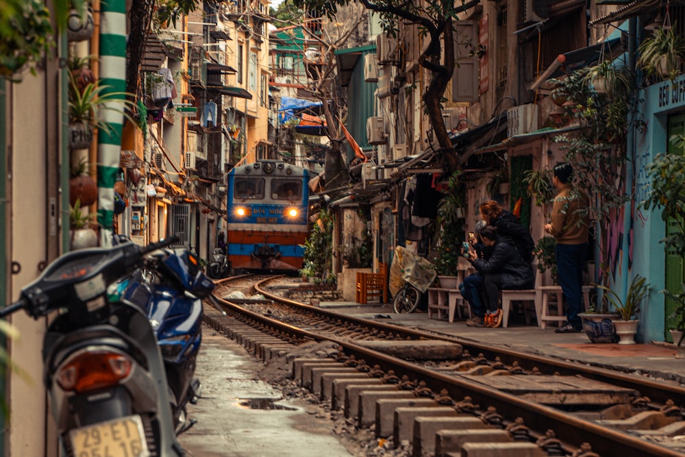 man in black jacket sitting on bench beside yellow train during daytime