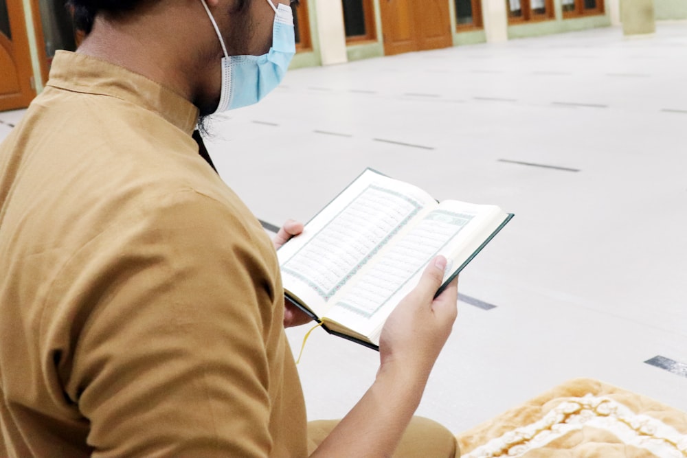 person in brown shirt holding white book