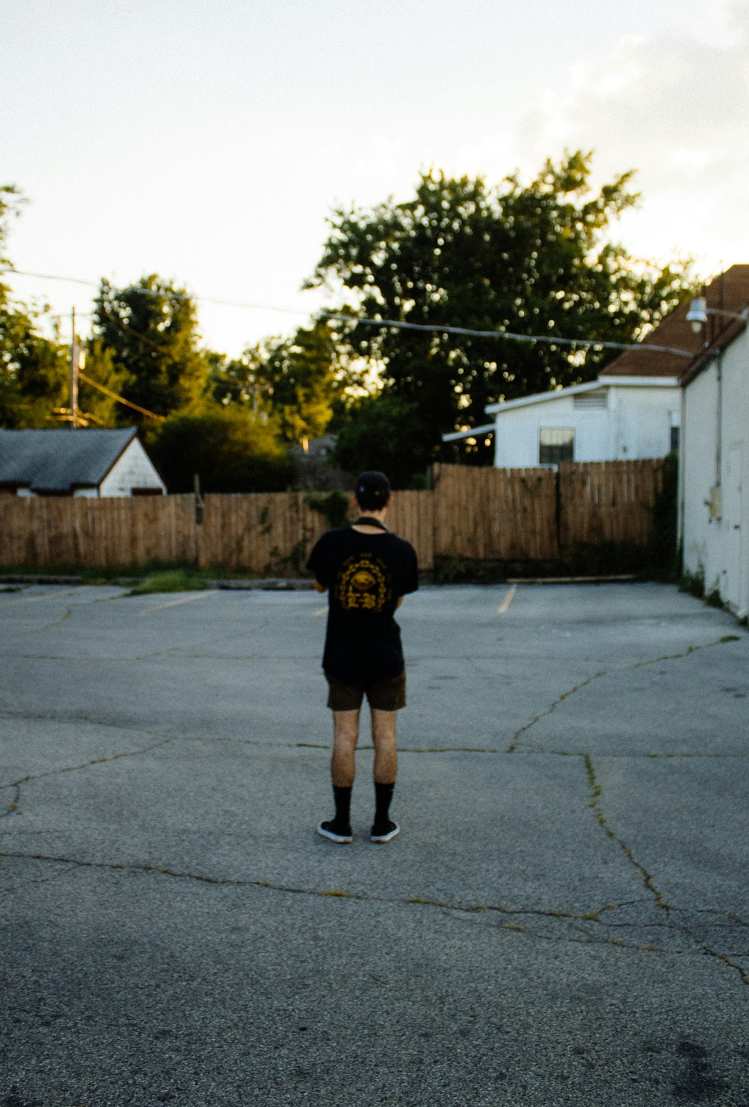 man in black t-shirt and black shorts walking on sidewalk during daytime