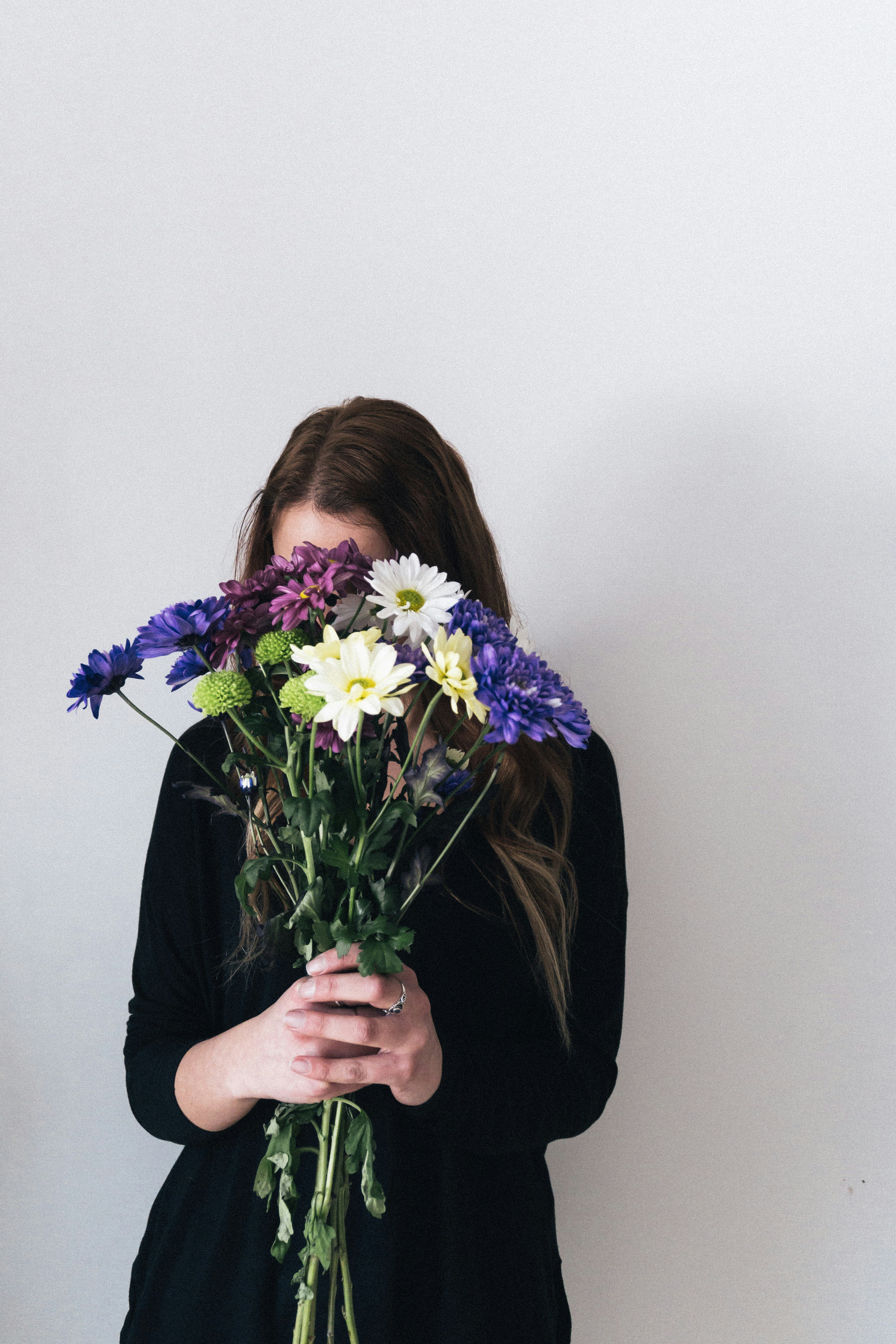 woman in black long sleeve shirt holding purple and white flower bouquet