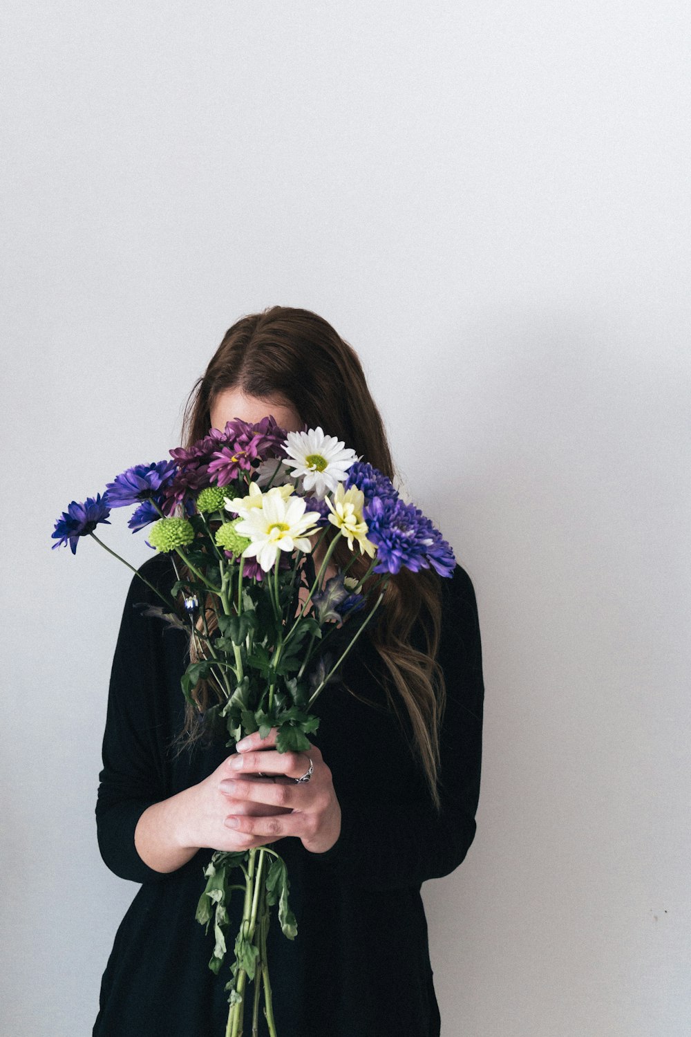 woman in black long sleeve shirt holding purple and white flower bouquet
