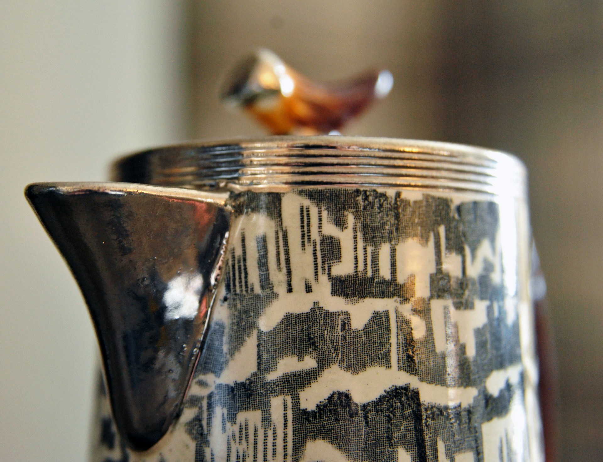 A close-up of a vibrant handmade ceramic bird trinket with intricate painted details.