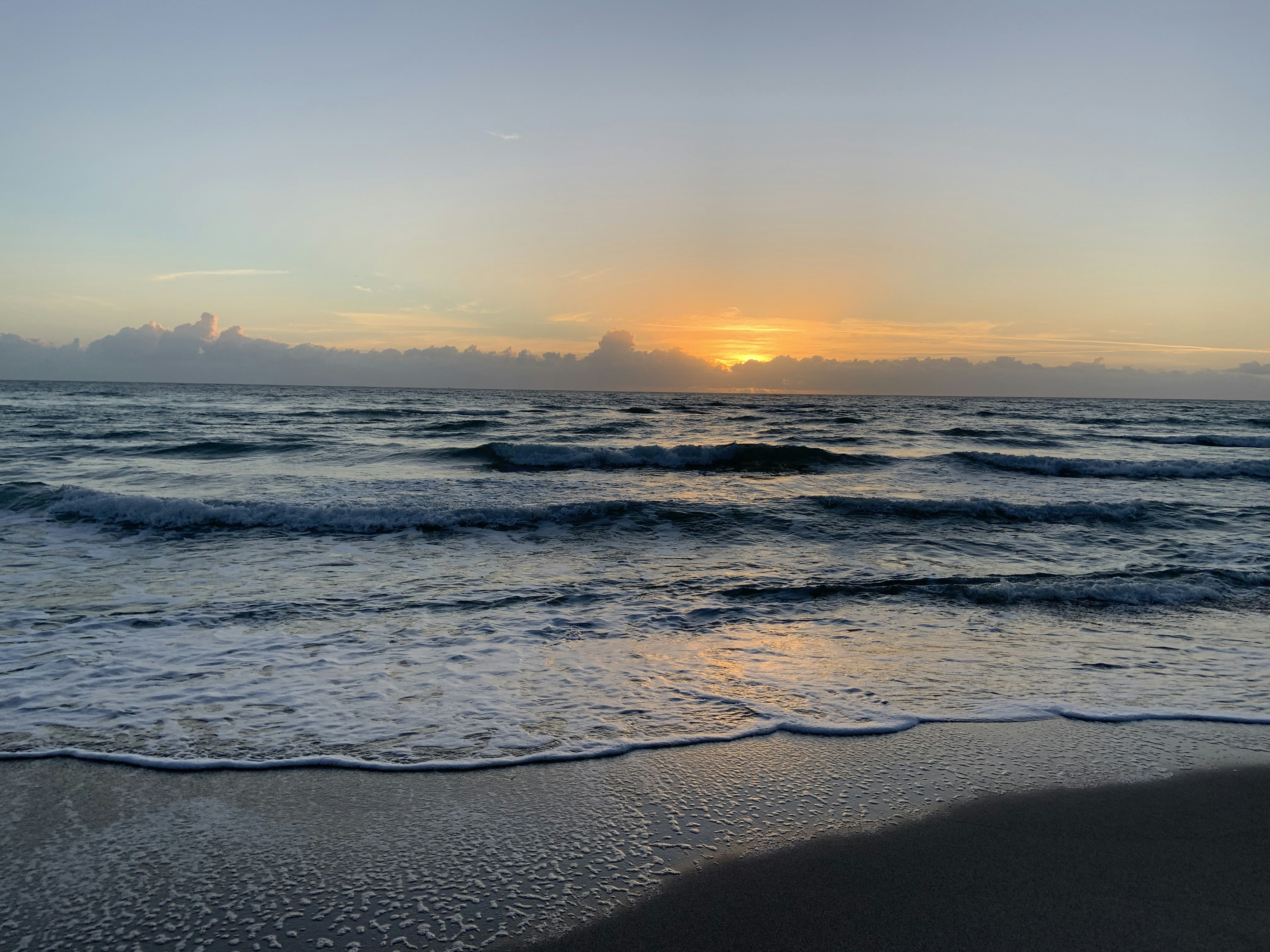 sea waves crashing on shore during sunset