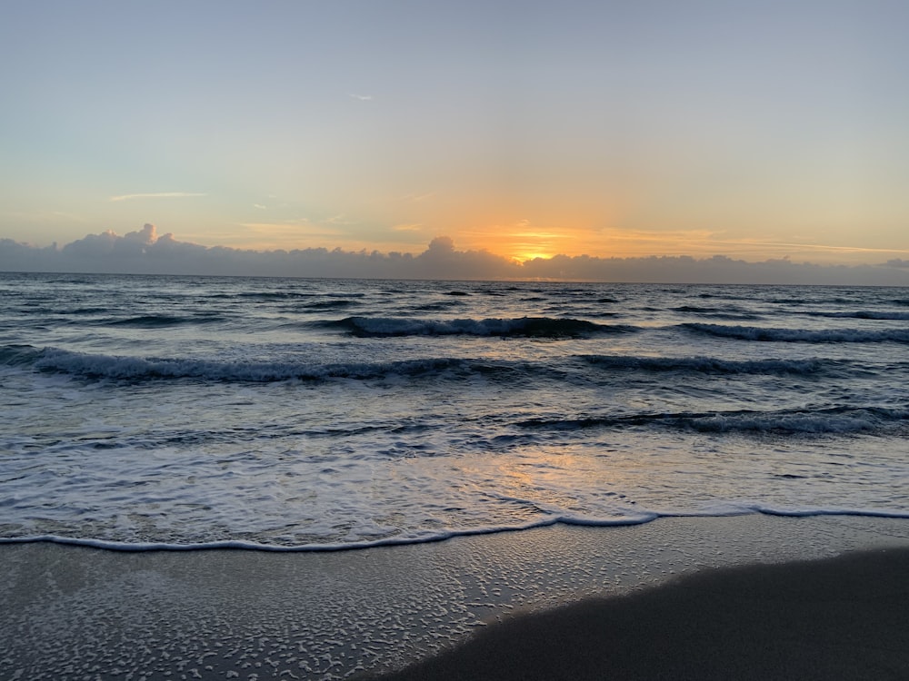 sea waves crashing on shore during sunset