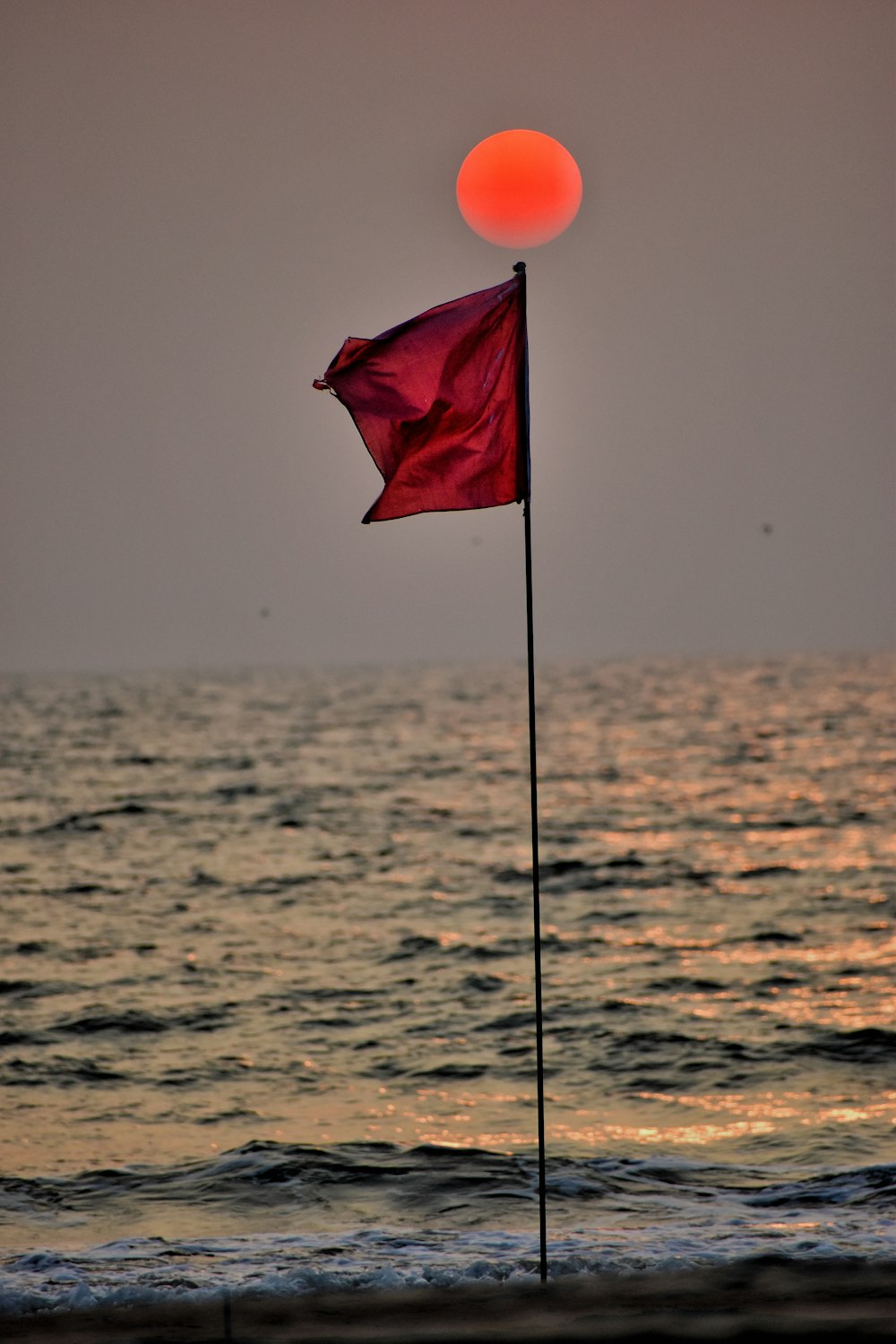 red flag on pole in the middle of the sea