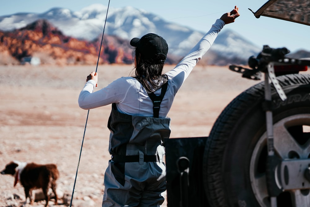 woman in white shirt and black backpack holding black fishing rod