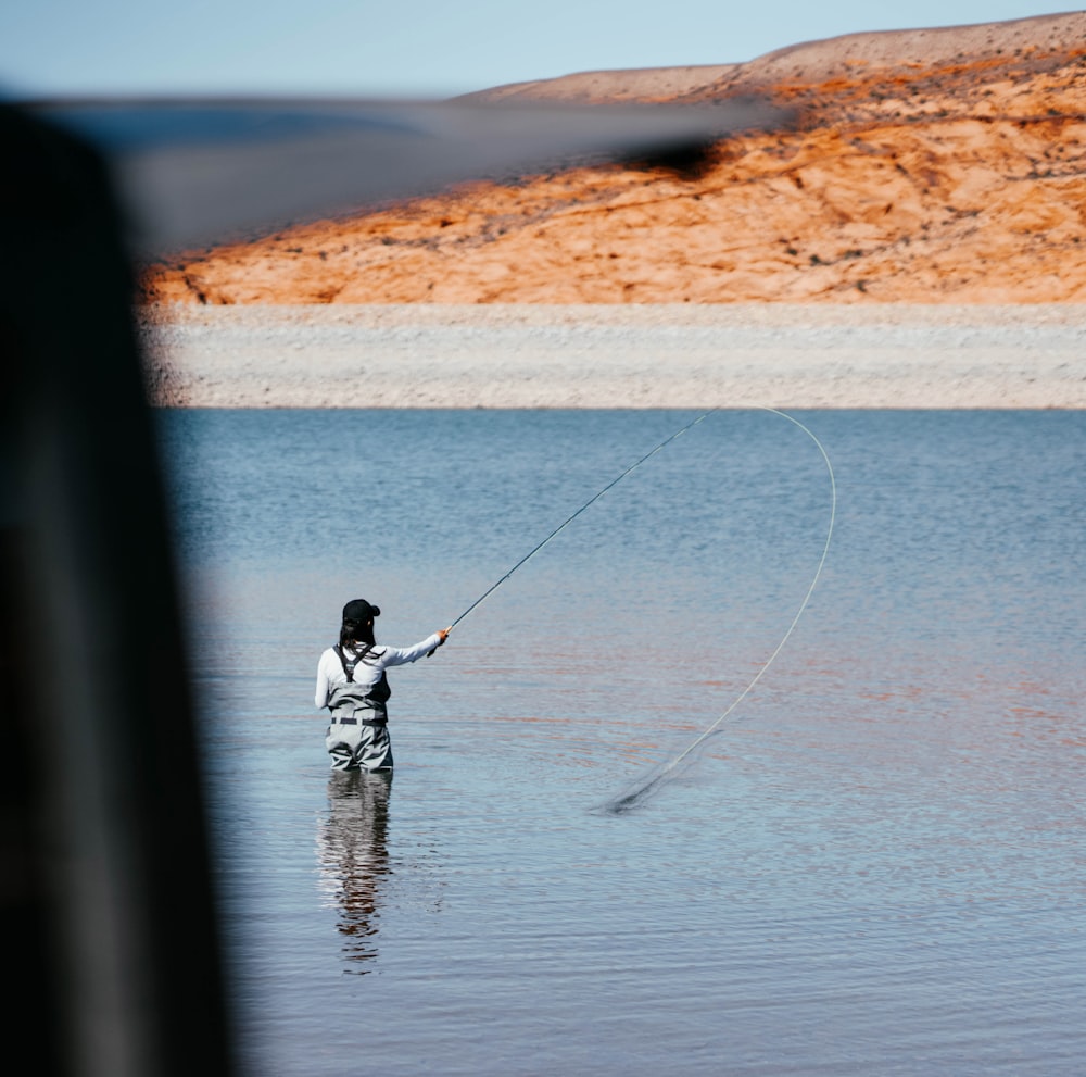 man in black jacket fishing on sea during daytime