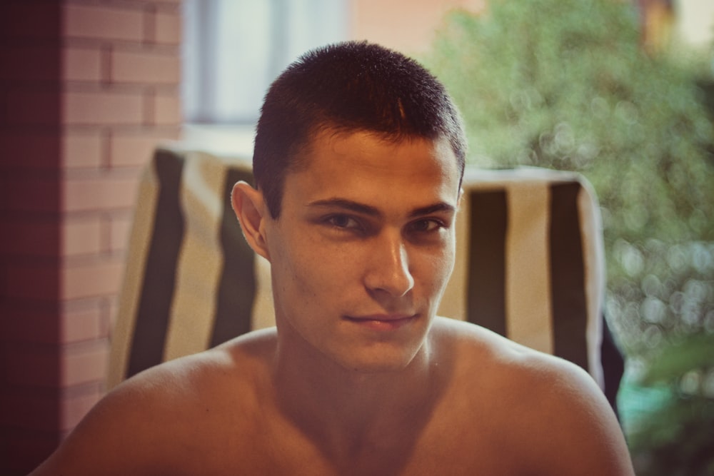 topless man sitting on black and white chair