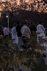 A group gathered in a circle outdoors, sharing stories and prayers at sunset.
