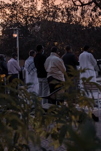 A small group praying together outdoors at sunset.