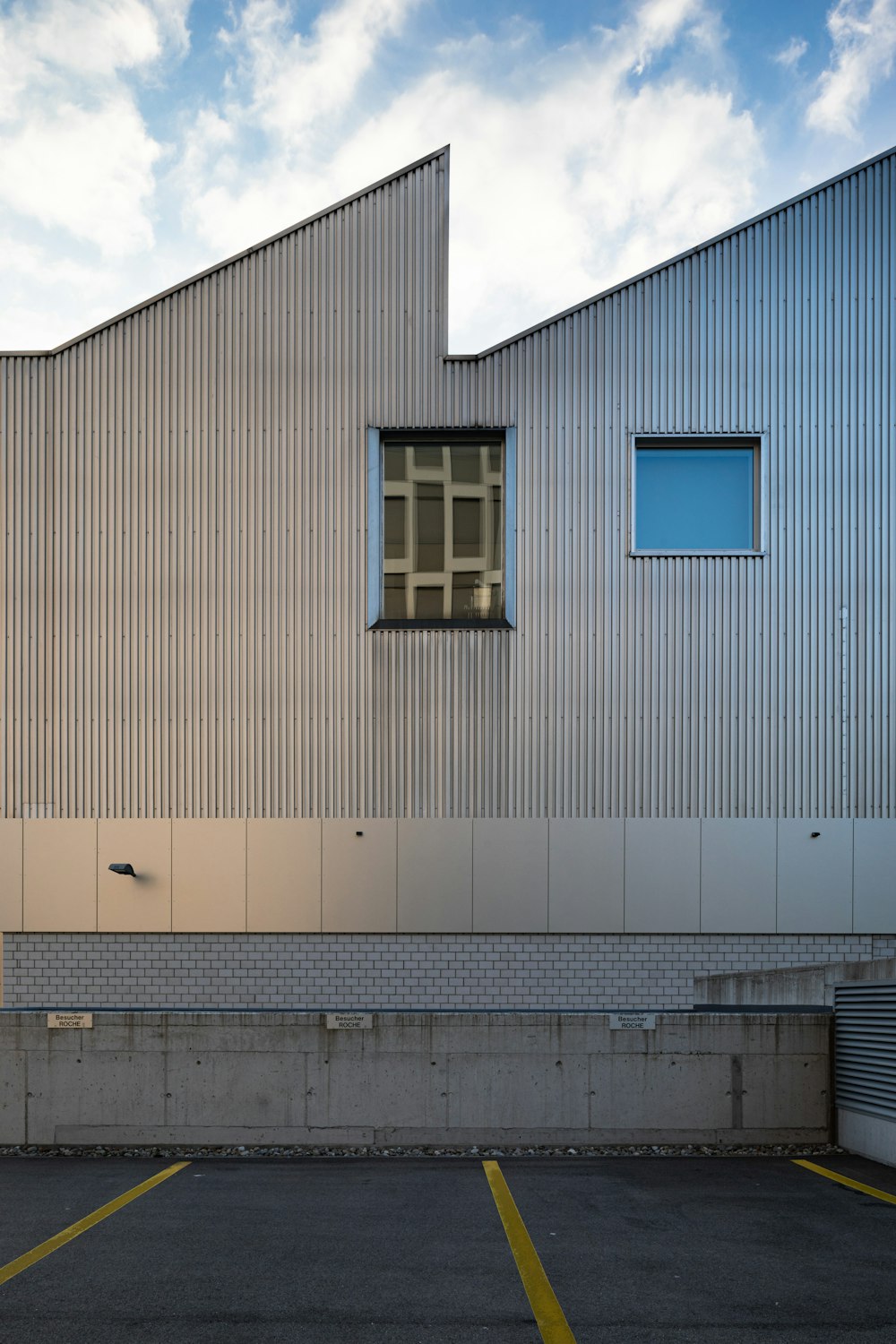 Edificio in cemento bianco e blu sotto nuvole bianche durante il giorno