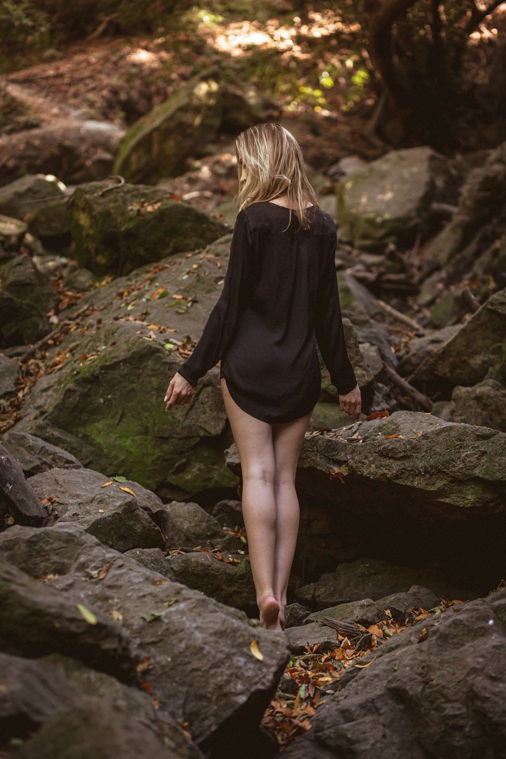 Femme en chemise noire à manches longues et jupe rose debout sur un sol rocheux pendant la journée