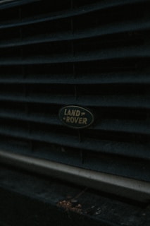 Close-up of a Land Rover badge on a rugged vehicle in a workshop setting