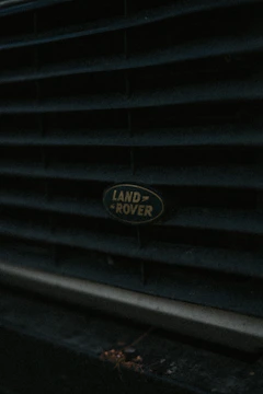 Close-up of a Range Rover's sleek front grille under bright workshop lights.