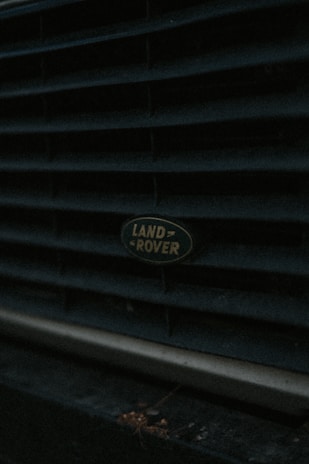 Close-up of a Land Rover badge on a rugged vehicle in a workshop setting