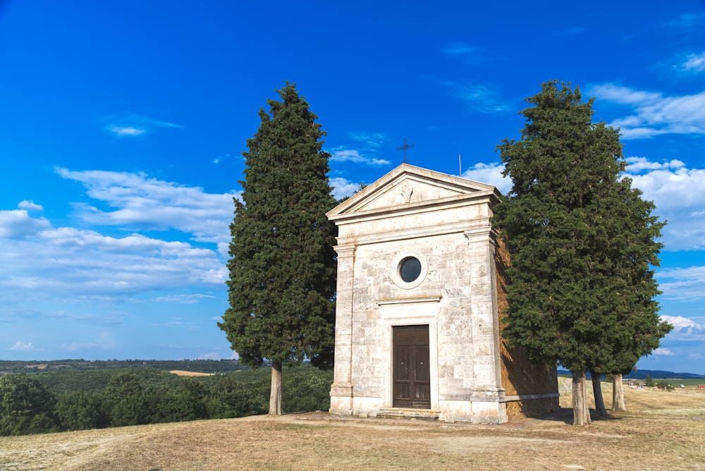 edificio in cemento bianco vicino agli alberi verdi sotto il cielo blu durante il giorno