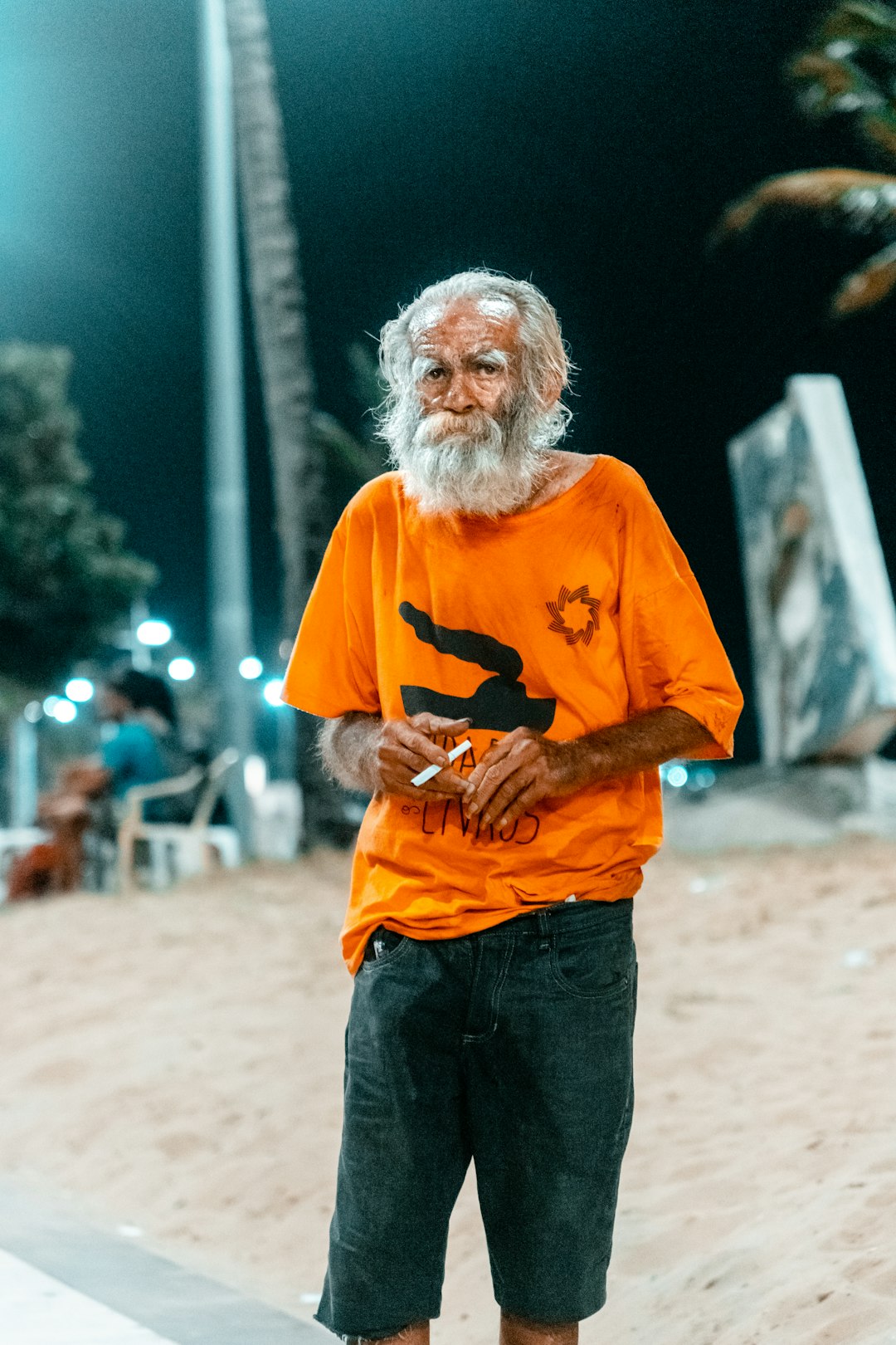 man in orange crew neck t-shirt standing on brown sand during daytime