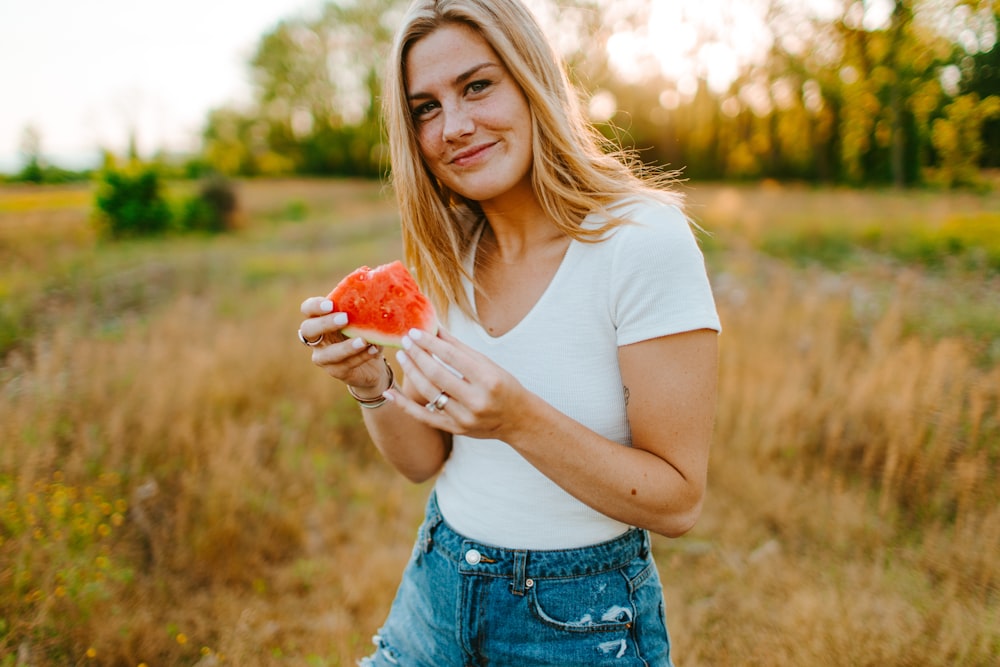 woman in white crew neck t-shirt holding red apple