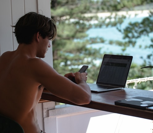 topless man using black laptop computer