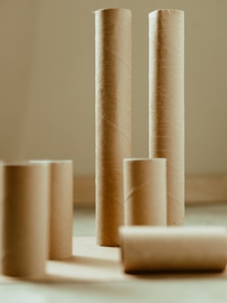 Several empty cardboard tubes of different heights are arranged on a surface, with shadows cast in different directions.