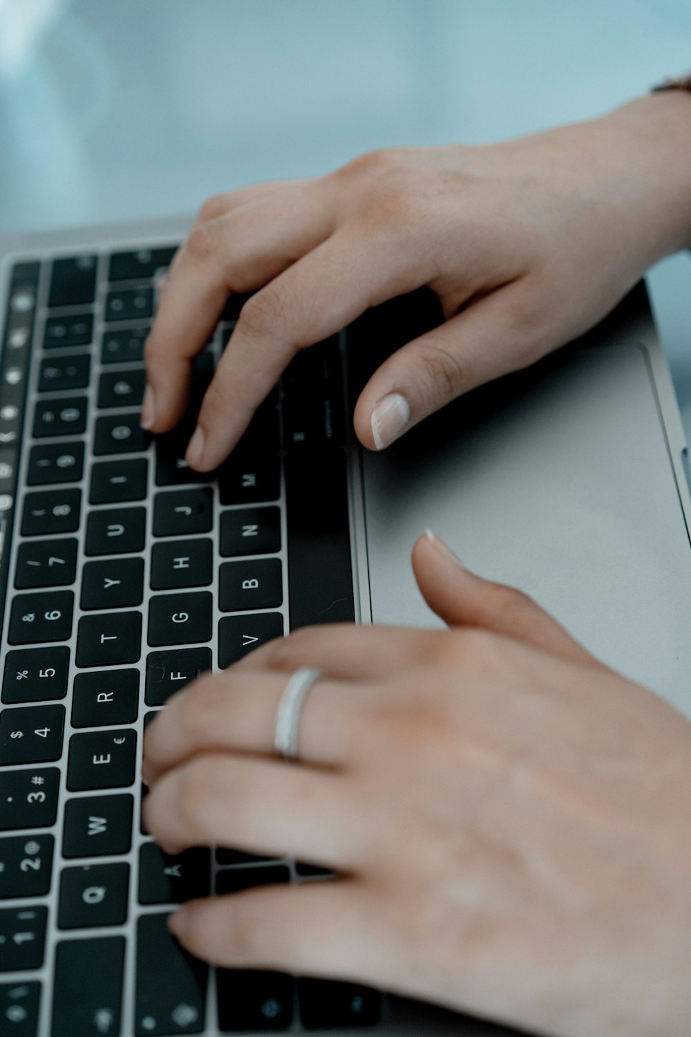 person wearing silver ring on macbook pro