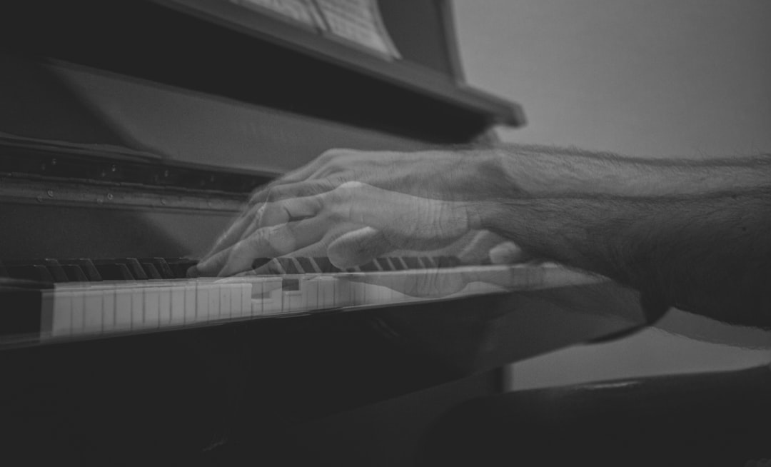 person playing piano in grayscale photography
