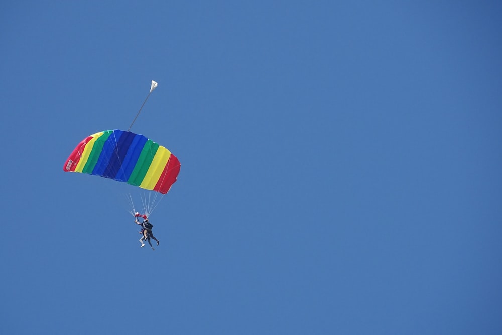 Persona en paracaídas bajo el cielo azul durante el día