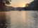 A peaceful outdoor scene with a person meditating near a calm lake at sunrise.