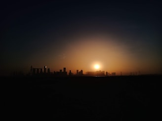 Sunset over a developing urban area with cranes and buildings.