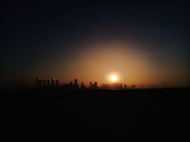 Sunset over a developing urban area with cranes and buildings.