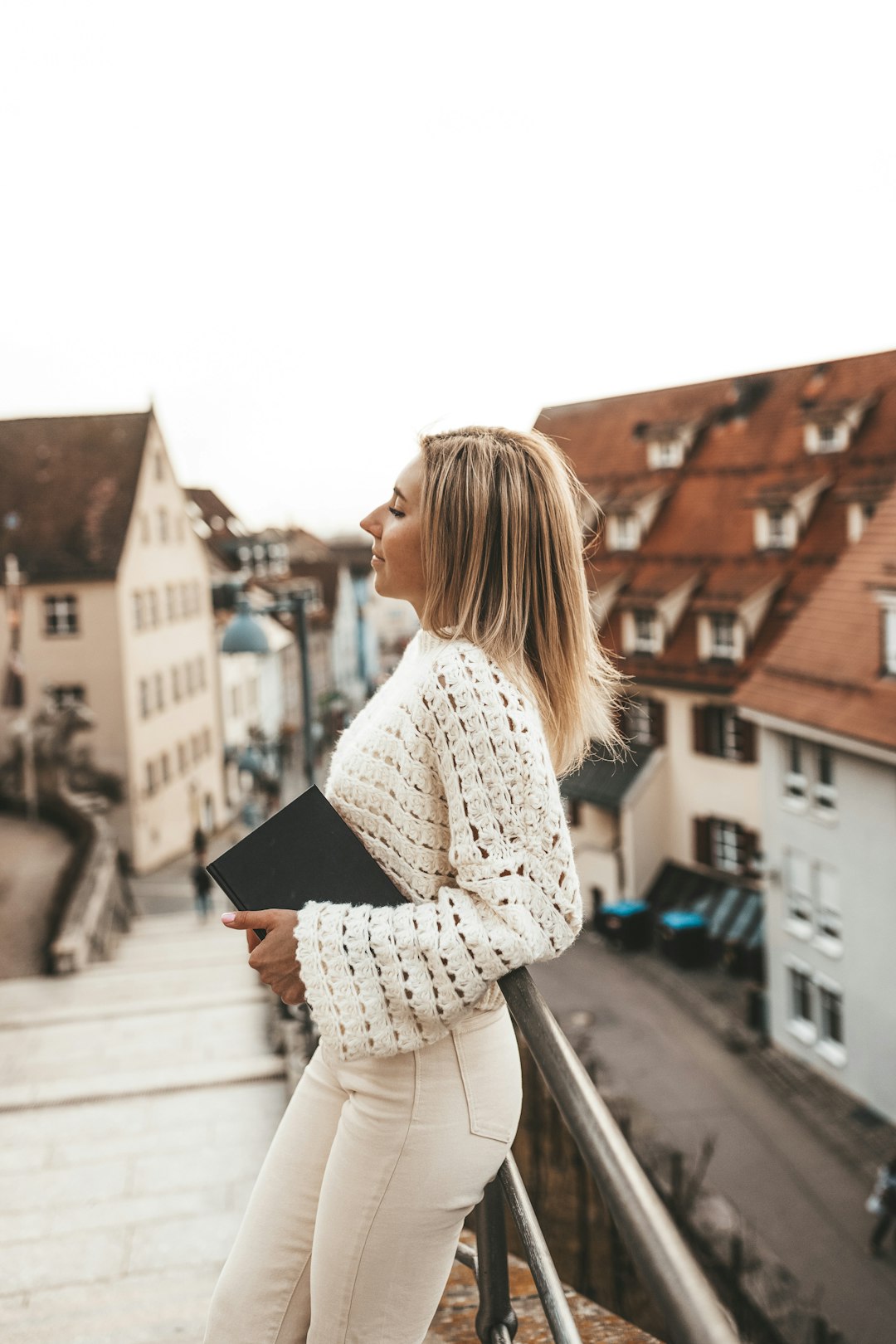 woman in white and black long sleeve shirt standing on sidewalk during daytime