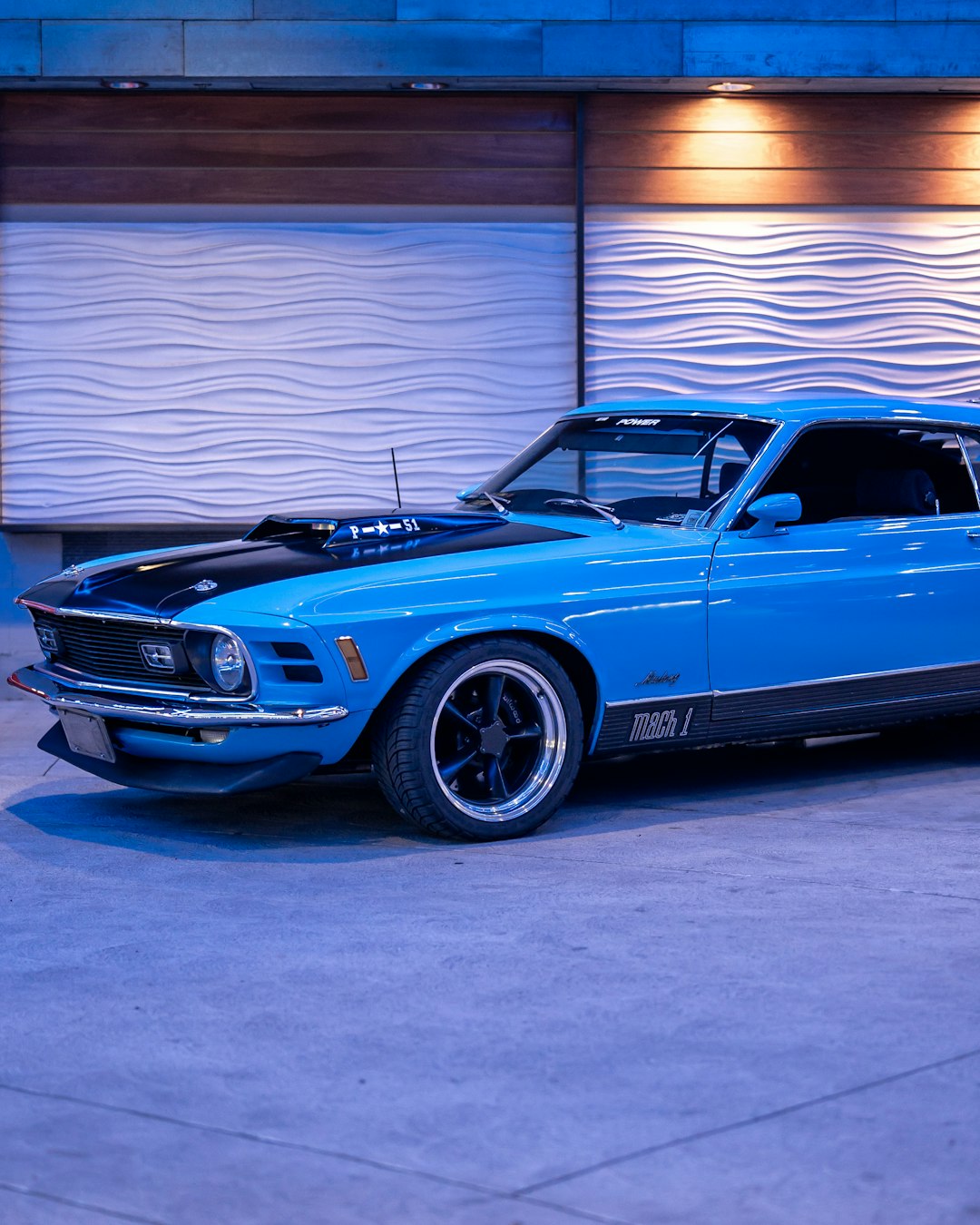 blue chevrolet camaro parked near white wall