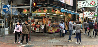 A lively street stand offering coffee and snacks with people chatting nearby.