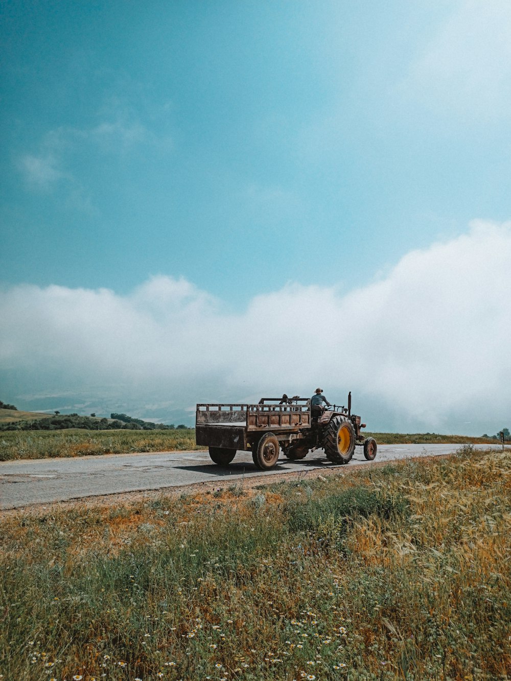 black truck on road under white clouds and blue sky during daytime