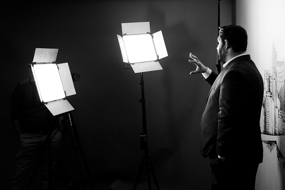 man in black jacket standing near white wall