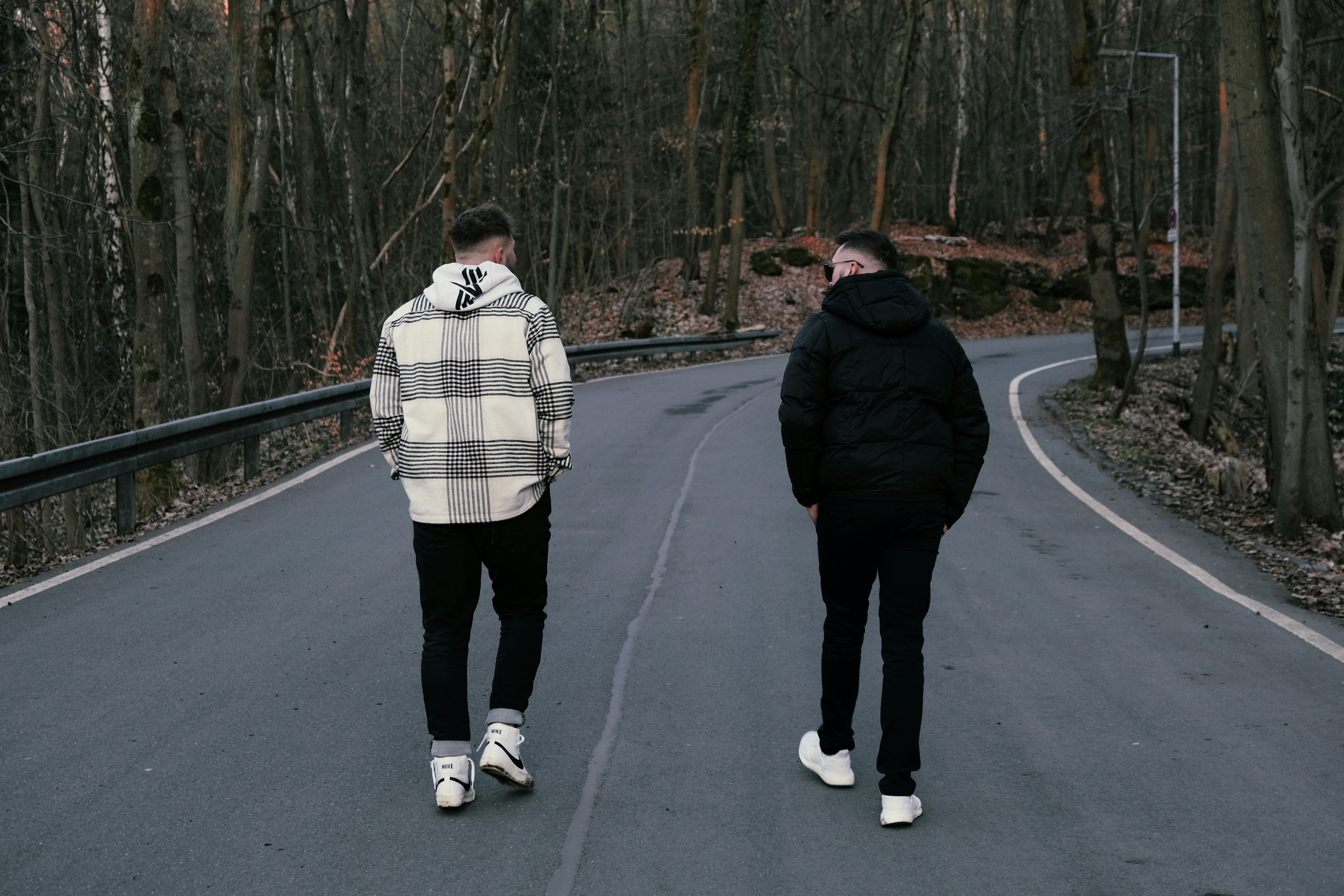 man in black jacket and white pants standing on gray concrete road during daytime