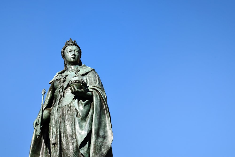 Statue d’homme en manteau sous le ciel bleu pendant la journée