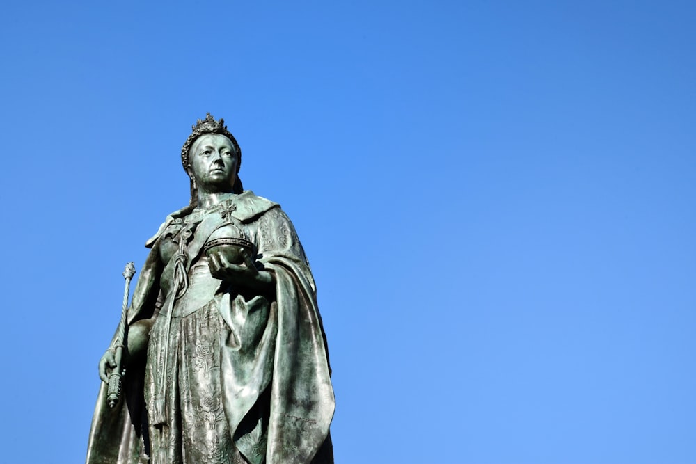 uomo in statua del cappotto sotto il cielo blu durante il giorno