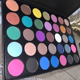Vibrant makeup palette arranged artistically on a sleek black surface.