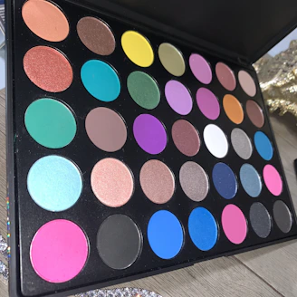 Vibrant makeup palette with bold colors arranged artistically on a marble surface.