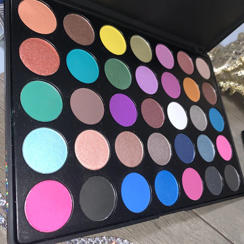 Vibrant makeup palette with bold colors arranged artistically on a marble surface.