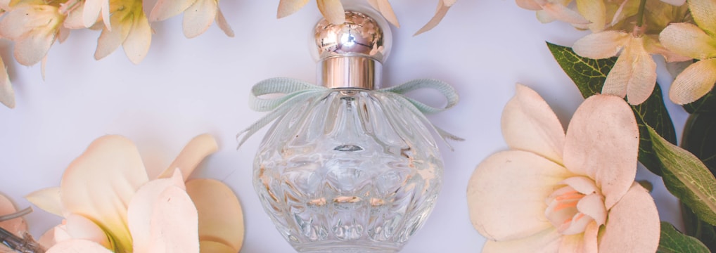 clear glass perfume bottle with white flowers