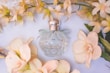Soft pastel-colored car perfume bottle surrounded by delicate flowers