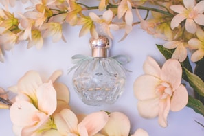 Transparent perfume bottle with floral design surrounded by fresh flowers